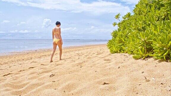 在萨努尔海滩上行走的女人