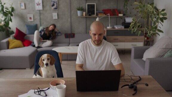 一个人在用笔记本电脑工作宠物狗就在他旁边