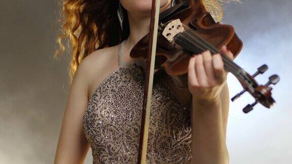 室内乐女孩小提琴手在闪光的衣服上演奏小提琴弓特写