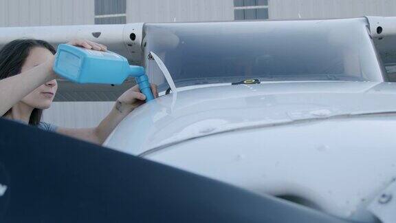 年轻的成年女飞行员正在检查一架小型单引擎飞机的发动机油箱上的油量尺