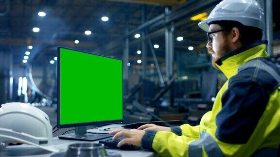 在重工业工厂里工业工程师使用绿色模拟屏幕在个人电脑上工作