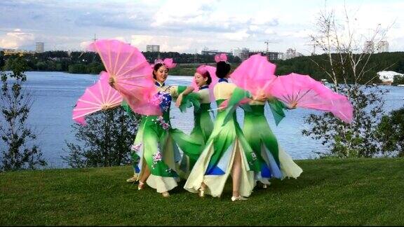五名亚洲女演员身着中国传统服饰与粉丝们在河边户外跳舞