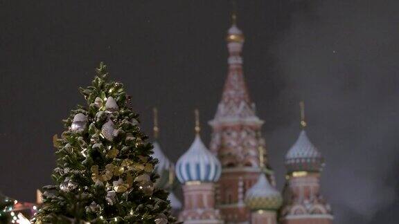 俄罗斯莫斯科红场上的新年红场上的圣巴西尔大教堂雪下降用球和花环装饰的新年树
