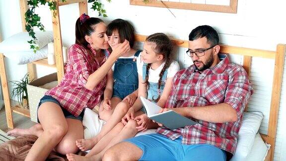 幸福的一家人躺在床上爸爸给女儿们读书慢镜头