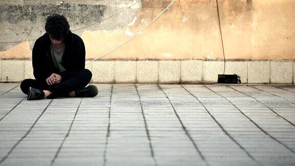 一个无家可归的人紧张地坐在地上抽着烟