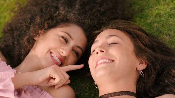 两个美丽的年轻女子躺在草地上享受阳光