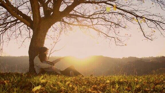 日落时分一对恩爱的情侣坐在树下