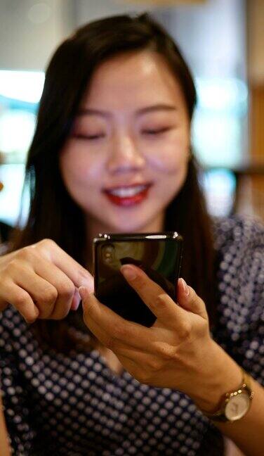 一名年轻的亚洲女子在咖啡馆里使用智能手机
