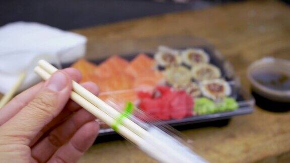 打开竹筷外卖塑料容器中的寿司费城卷和鳗鱼卷酱油粉姜芥末寿司配送理念