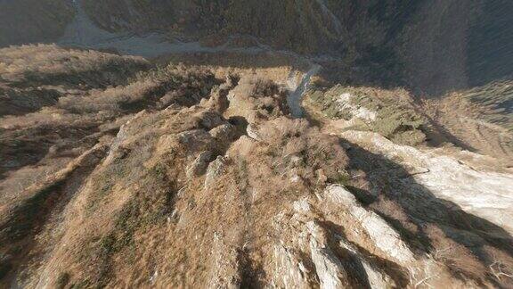 FPV无人机潜水拍摄接近岩石山坡和悬崖在阳光山谷石质河流纹理岩石山从极端下降速度飞行运动直升机