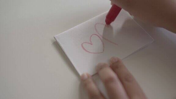女人用蜡笔在白纸上画了一个红心的形状