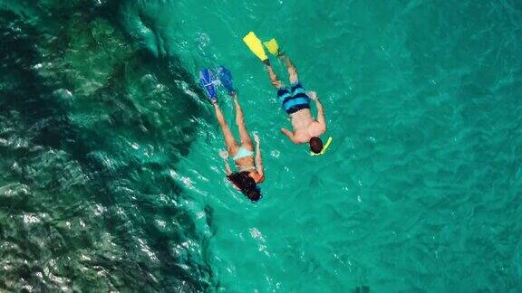 年轻夫妇在热带蓝色海洋浮潜的鸟瞰图