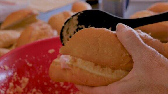 将凉拌卷心菜放入三明治卷的手的特写