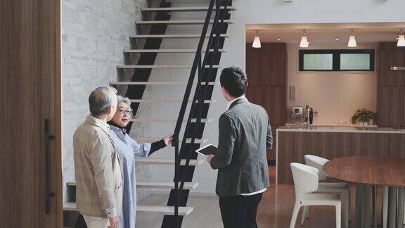 一位男性房地产经纪人正在向一对老夫妇展示房子