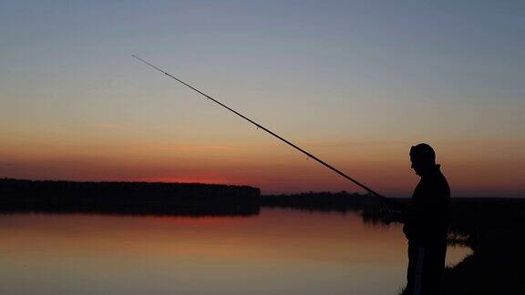 渔夫在日落时在湖边钓鱼