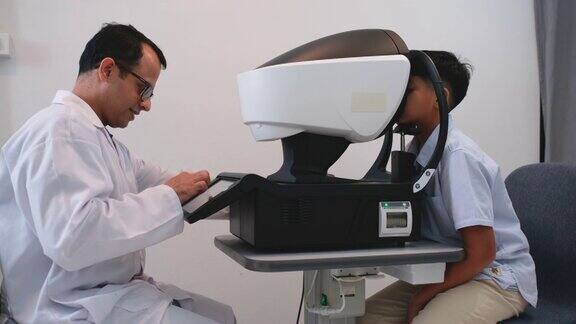 眼科医生在诊断过程中在眼镜店用机器测量男孩的视力为男孩准备治疗或制作合适的眼镜