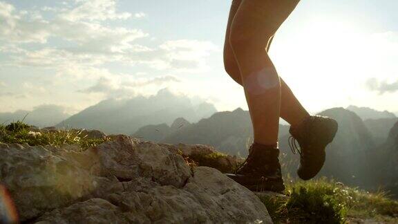 特写:皮革山鞋和女性攀登陡峭的山顶的细节