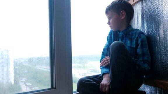 男孩在雨中看着窗外很伤心