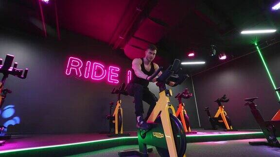 骑自行车做有氧运动的男人运动员在健身房骑自行车的镜头
