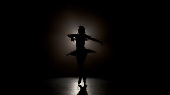 一个年轻美丽的芭蕾舞者的剪影穿着尖头鞋和做优雅的脚尖旋转在慢动作