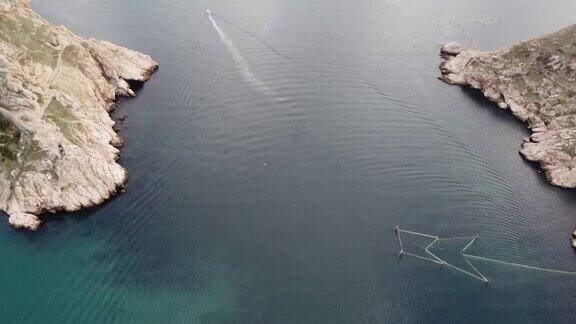 鸟瞰多个游艇和帆船在港口海洋或海湾与蓝色的绿松石海水在城市或城镇海湾、山脉、岩石、堤岸和城市建筑