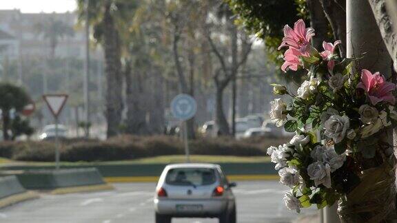 路灯上的花纪念一场交通事故和汽车在路上行驶