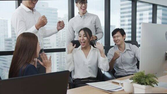 4K超高清:一群亚洲业务员工在现代化的办公室欢呼击掌