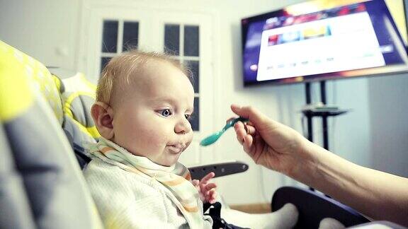 小男孩一边看电视一边用勺子吃麦片