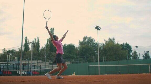 慢动作:年轻的白人女子网球运动员在比赛或练习中发球在红土球场发球的网球运动员