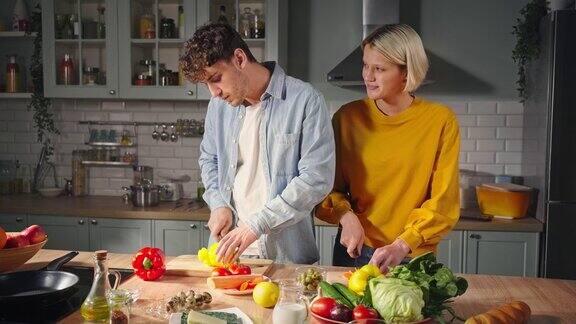 相爱的情侣一起分享快乐的时刻在家里的厨房里准备健康的素食沙拉