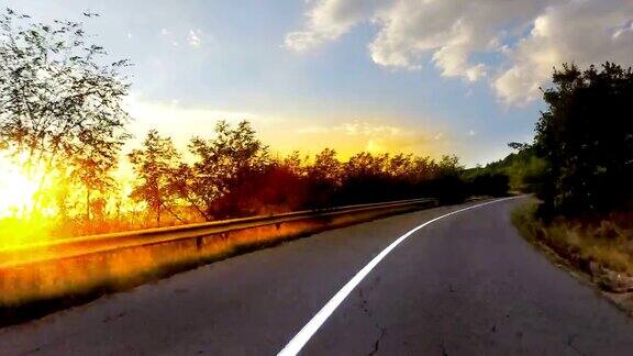 日落开车在乡村的山路上开车夕阳西下