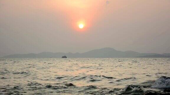 在夕阳的背景下小海浪拍打着海滩上的岩石