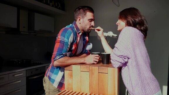 女人在厨房给面带微笑的男友吃饼干