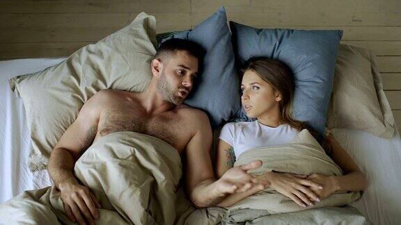 俯视图的年轻夫妇躺在床上心烦意乱彼此争吵