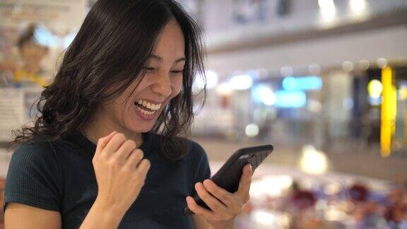 亚洲女性使用智能手机获胜概念庆祝成功