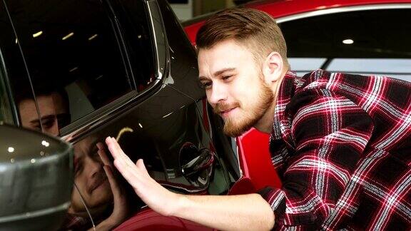 英俊的胡子男性顾客检查汽车油漆在经销商的一辆新汽车