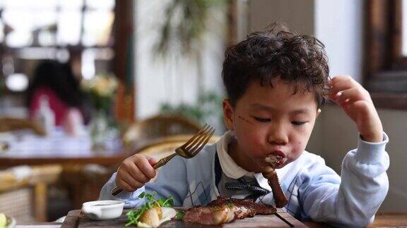 一个小男孩在餐厅吃牛排