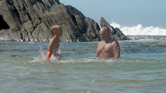 可爱的男孩在平静的海湾溅水给爸爸玩