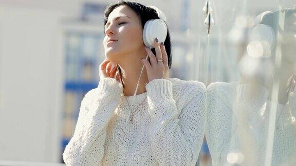 戴着白色耳机的女人在玻璃建筑里享受音乐