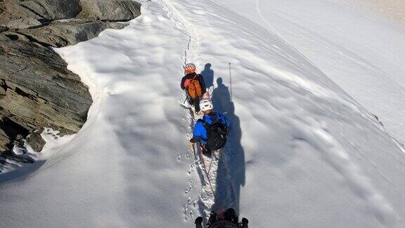 高级登山队正在向欧洲阿尔卑斯山积雪覆盖的山峰进发使用绳索和攀爬设备