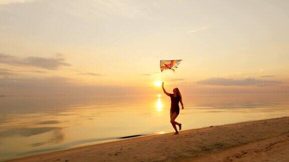 快乐的年轻女子拿着风筝奔跑在日落时