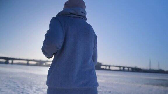 女孩在冬天沿着白雪覆盖的沙滩跑步