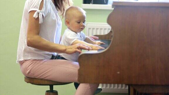 母亲和蹒跚学步的男婴在家里弹钢琴孩子学习