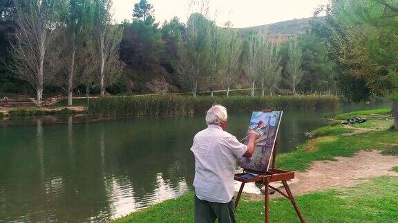 一位上了年纪的艺术家在河岸上画油画