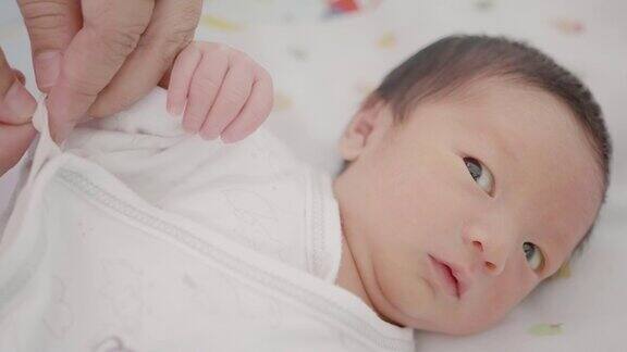 快乐的亚洲家庭母亲打扮新生婴儿(0-1个月)男婴