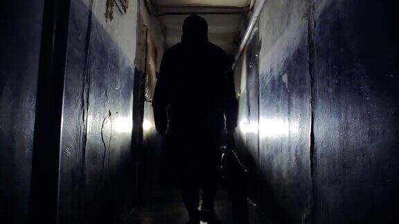 穿着黑色夹克背着包的匪徒沿着走廊离开摄像头