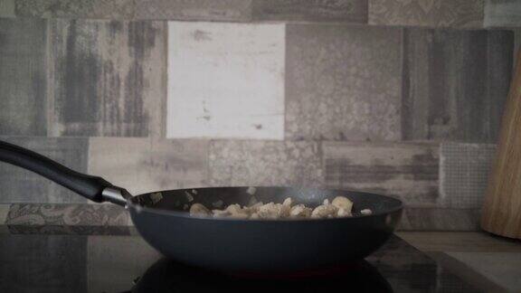 将准备好的洋葱和蘑菇切入锅中行动近距离观察新鲜洋葱和香槟酒在厨房的平底锅里油炸