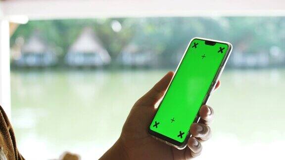 使用绿色屏幕的智能手机在自然与湖泊背景色度键