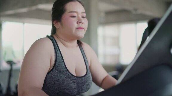 超重女性在跑步机上进行有氧运动在健身房里进行锻炼