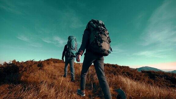 两名爬山的背包徒步旅行者背影慢镜头